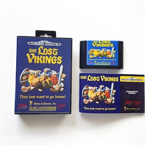 Puede incluir: Un cartucho de juego Sega Mega Drive, un manual de instrucciones y una caja de juego para el juego "The Lost Vikings". La caja del juego es azul con una imagen de tres vikingos. El texto "They just want to go home!" est&aacute; impreso en la caja. El manual de instrucciones tambi&eacute;n es azul con una imagen de los vikingos. El texto "They just want to go home!" est&aacute; impreso en el manual.