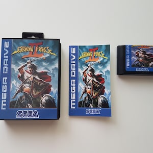 Könnte beinhalten: Eine Sega Mega Drive-Spielkassette, eine Schachtel und eine Anleitung für Shining Force II. Die Schachtel ist blau und zeigt den Titel und das Logo des Spiels. Die Kassette ist schwarz mit einem blauen Etikett. Die Anleitung ist ein gefaltetes Heft mit einem blauen Umschlag.