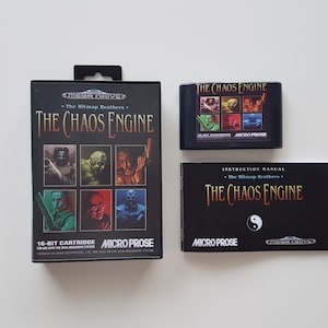 Puede incluir: Un cartucho de juego Sega Genesis, un manual de instrucciones y una caja para el juego "The Chaos Engine" de MicroProse. La caja presenta un fondo negro con un título en letras doradas y una cuadrícula de seis retratos de personajes. El manual de instrucciones tiene una cubierta negra con el título del juego en letras blancas y un símbolo yin-yang.