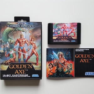 Op de afbeelding: Een Sega Mega Drive videogame set voor "Golden Axe". De set bevat de spelcartridge, de handleiding en de doos. De dooskunst toont gespierde figuren en een draak. De cartridge en handleiding tonen ook de titel van het spel.