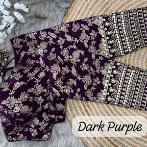 May include: A dark purple blouse featuring intricate silver floral embroidery across the body and sleeves. The cuffs are detailed with horizontal bands of geometric patterns and sequins. The garment includes thin tie-up strings at the neckline.