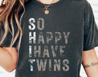 May include: A dark gray t-shirt with a white distressed graphic that reads "So Happy I Have Twins".