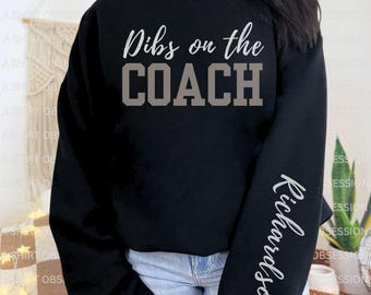 Peut inclure: Sweat-shirt noir avec le texte "Dibs on the COACH" en lettres grises. La manche droite porte le nom "Richardson" écrit verticalement en lettres grises.