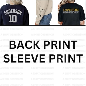 May include: Three different t-shirts with custom designs. The first t-shirt is navy blue with white text that says "Anderson 10" on the back. The second t-shirt is beige with black cursive writing that says "Bradlee" on the left sleeve. The third t-shirt is black with gold text that says "Davison Irish Dance Academy".