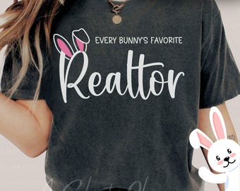 May include: A dark gray t-shirt with the text "Every Bunny's Favorite Realtor" in white. The text is accompanied by a white bunny ear graphic with pink accents.