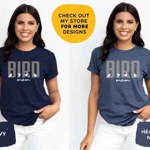 May include: Two women wearing navy blue t-shirts with the text "BIRD MOM" and a graphic of birds. The t-shirt on the left is navy blue, and the t-shirt on the right is heather navy.