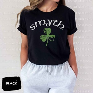 May include: Black t-shirt with a green shamrock and the word "smyth" in white lettering.