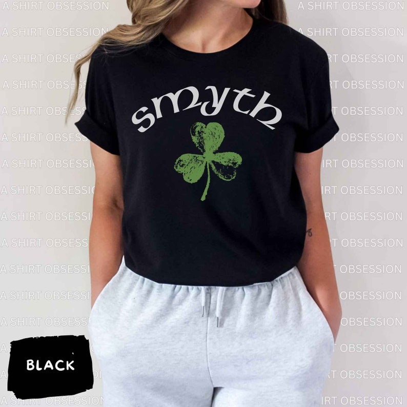 May include: Black t-shirt with a green shamrock and the word "smyth" in white lettering.