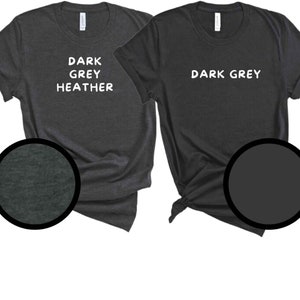 May include: Two dark grey t-shirts. One is dark grey heather, the other is dark grey. The text "DARK GREY HEATHER" and "DARK GREY" are printed in white on the shirts. Close-up circles show the fabric texture.