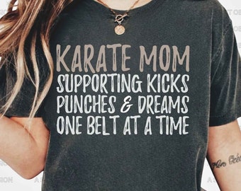 May include: A gray t-shirt with the text "KARATE MOM SUPPORTING KICKS PUNCHES & DREAMS ONE BELT AT A TIME" in white.