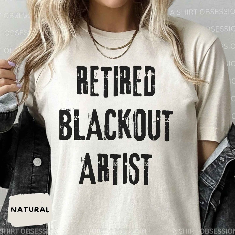 May include: A beige t-shirt with the text "Retired Blackout Artist" printed in black. The text has a distressed, vintage look.