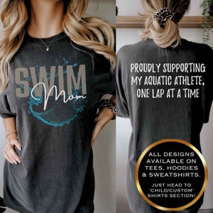 Może przedstawiać: Szary T-shirt z napisem "Swim Mom" w kolorze szarym i niebieskim wzorem rozpryskującej się wody. Z tyłu koszulki znajduje się napis "Proudly supporting my aquatic athlete, one lap at a time".