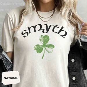 May include: A white t-shirt with a green shamrock and the word "smyth" in black lettering.