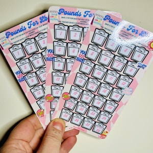 May include: Three pink and white weight loss trackers with a scale design. Each tracker has 28 scales with numbers 1-28. The text on the tracker reads "Pounds For Lbs" and "Save £100 for each lb you loose on your weight journey. This tracker saves £28.00 which equals 2 stone."