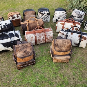 K&ouml;nnte beinhalten: Eine Sammlung von 14 Taschen aus Kuhfell in verschiedenen Stilen, darunter Rucks&auml;cke und Reisetaschen. Die Taschen sind alle braun und wei&szlig; mit einem gepunkteten Muster.