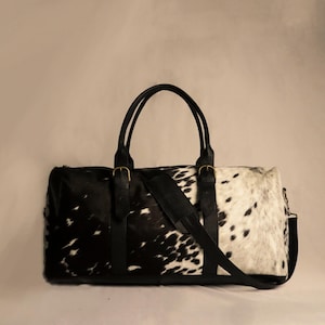 Personalized Large Cowhide Duffel Bag made from genuine hair-on leather. This unisex, handmade travel bag is perfect for weekend getaways or daily use. Spacious and stylish with multiple compartments, it offers both function and flair. The adjustable strap adds comfort, while real cowhide ensures each bag is unique. A thoughtful gift for him or her. Note: Natural cowhide patterns vary, making every piece one-of-a-kind.