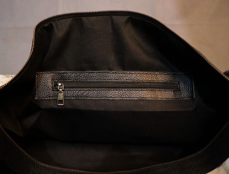 Personalized Large Cowhide Duffel Bag made from genuine hair-on leather. This unisex, handmade travel bag is perfect for weekend getaways or daily use. Spacious and stylish with multiple compartments, it offers both function and flair. The adjustable strap adds comfort, while real cowhide ensures each bag is unique. A thoughtful gift for him or her. Note: Natural cowhide patterns vary, making every piece one-of-a-kind.
