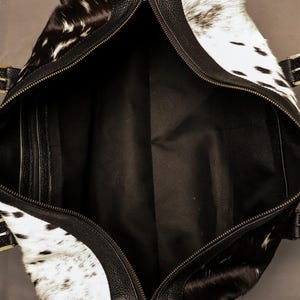 Personalized Large Cowhide Duffel Bag made from genuine hair-on leather. This unisex, handmade travel bag is perfect for weekend getaways or daily use. Spacious and stylish with multiple compartments, it offers both function and flair. The adjustable strap adds comfort, while real cowhide ensures each bag is unique. A thoughtful gift for him or her. Note: Natural cowhide patterns vary, making every piece one-of-a-kind.