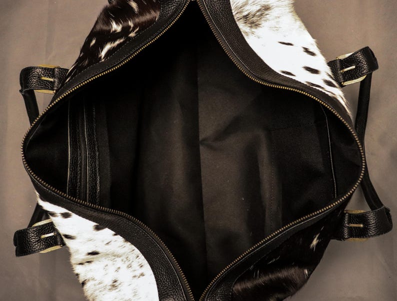 Personalized Large Cowhide Duffel Bag made from genuine hair-on leather. This unisex, handmade travel bag is perfect for weekend getaways or daily use. Spacious and stylish with multiple compartments, it offers both function and flair. The adjustable strap adds comfort, while real cowhide ensures each bag is unique. A thoughtful gift for him or her. Note: Natural cowhide patterns vary, making every piece one-of-a-kind.