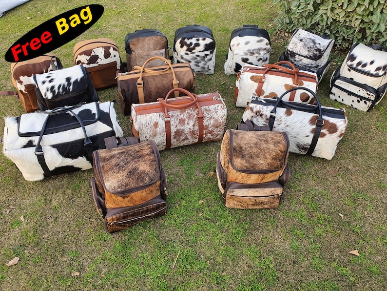 K&ouml;nnte beinhalten: Eine Sammlung von Taschen aus Kuhfell in verschiedenen Stilen, darunter Rucks&auml;cke und Reisetaschen. Die Taschen sind alle braun und wei&szlig; mit einem gefleckten Muster. Der Text "Free Bag" ist in der oberen linken Ecke des Bildes sichtbar.