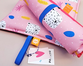 Könnte beinhalten: Eine rosa Stoffmatte mit weißem Leopardenmuster sowie blauen, gelben und rosa Blattmotiven. Die Matte verfügt über ein blaues Gummiband, ein kleines orangefarbenes Etikett mit der Aufschrift YEAH und ein weißes Papieretikett mit einem rosa Herz und dem Text PALSHO.