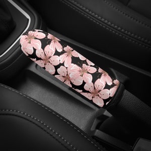 May include: A pink and black floral patterned car gear shift knob cover. The cover is made of soft fabric and is designed to protect the gear shift knob from wear and tear.