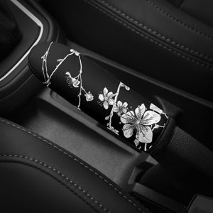 May include: Black car interior with a white floral patterned gear shift knob.