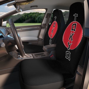 May include: Two black car seat covers with a red circle and the word "TOKYO" written in white inside the circle. The word "TOKYO" is written vertically in a stylized font.
