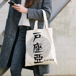 May include: A white tote bag with black text and a black and white graphic design. The text on the bag reads "HEATHER".