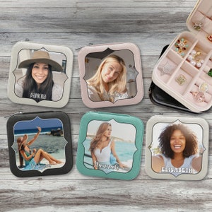 May include: Five small, square, fabric jewelry boxes with a decorative frame around a photo of a person. The boxes are in different colors: black, beige, light blue, pink, and white. Each box has a name printed on the bottom: Ramona, Heather, Hannah, Elisabeth.