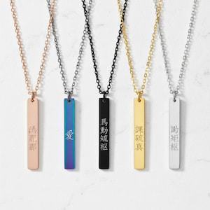 May include: Five pendant necklaces with rectangular charms and chain. The charms are in rose gold, iridescent blue, black, gold, and silver. Each charm has a different Chinese character engraved on it.