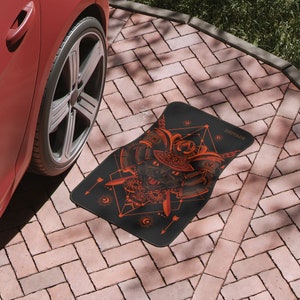 May include: Black car mat with a red and black illustration of a cat wearing a samurai helmet. The text "INVADER" is printed on the mat.