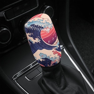 May include: A blue, white, and pink gear shift knob with a Japanese wave design and the word "Drive" in Japanese.