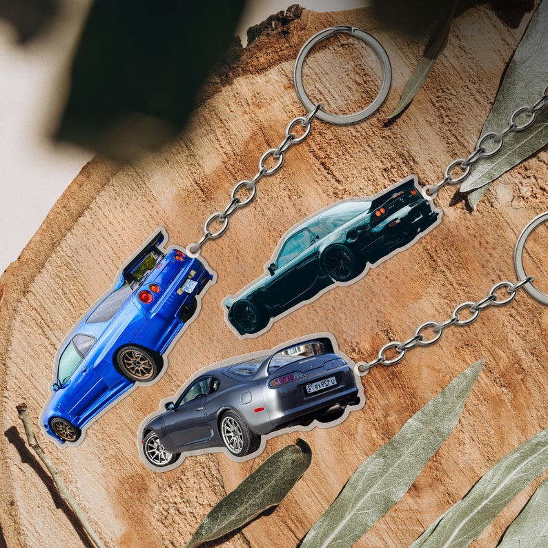May include: Three car keychains featuring a blue, silver, and black car. The keychains are attached to silver metal rings.