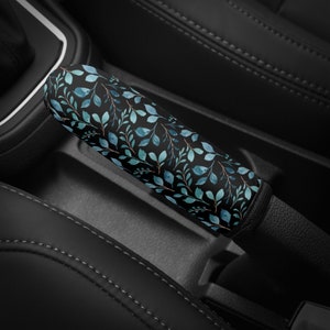 May include: A black car gear shift knob cover with a blue and green floral pattern.