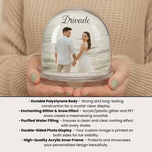 Może przedstawiać: Przezroczysta kula śnieżna ze zdjęciem pary trzymającej się za ręce na plaży. Na g&oacute;rze napis "Drivade" w ozdobnej czcionce. Kulę trzyma osoba.
