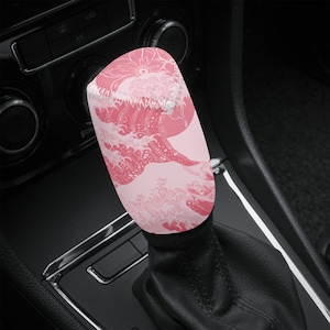 May include: Pink and white car gear shift knob with a wave pattern.