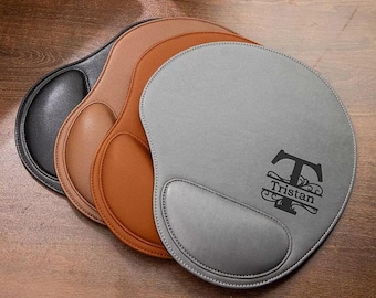 May include: Three personalized leather mouse pads in gray, brown, and black. The gray mouse pad has a monogrammed initial "T" with the name "Tristan" underneath.