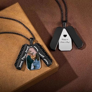 May include: Black necklace with a photo locket pendant. The locket opens to reveal a photo of a family. The back of the locket has the inscription "Happy 1st Father's Day!"