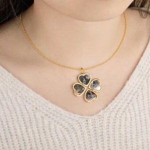 May include: A gold necklace with a four-leaf clover pendant. Each leaf is a heart-shaped locket that opens to reveal a small photo.