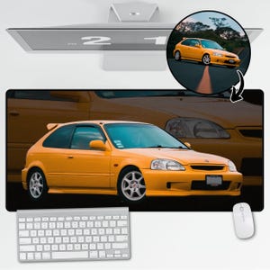 May include: A yellow Honda Civic Si with black trim and tinted windows. The car is parked on a paved road with a black asphalt surface.