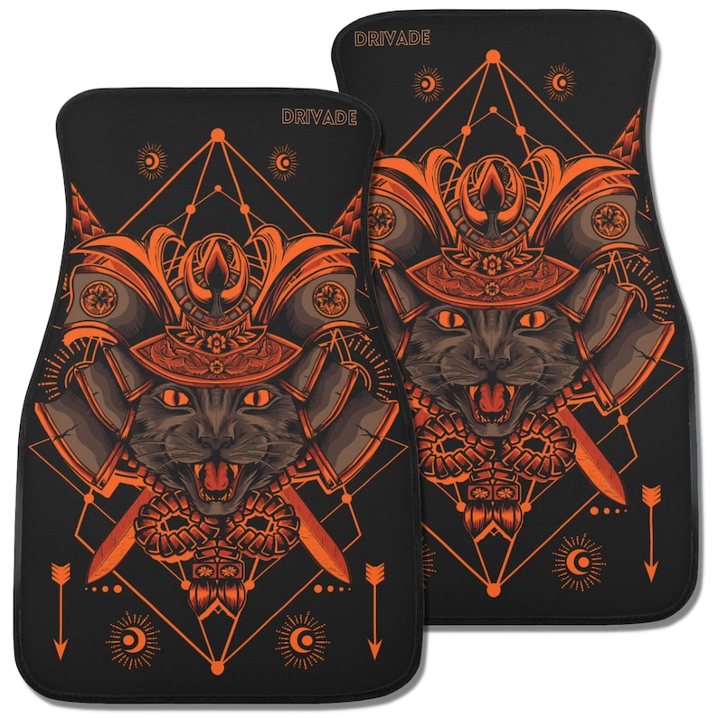 May include: A pair of black car floor mats with an orange geometric design featuring a cat wearing a samurai helmet. The mats have the word "Drivade" printed on them.