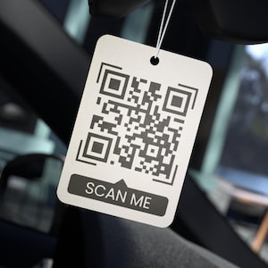 May include: A white tag with a black and white QR code and the text "SCAN ME" printed on it.