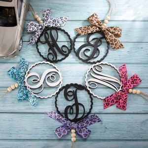 Peut inclure: Six ornements ronds en bois avec différentes lettres au centre. Chaque ornement est orné d'un ruban à imprimé léopard noué autour avec une perle en bois.