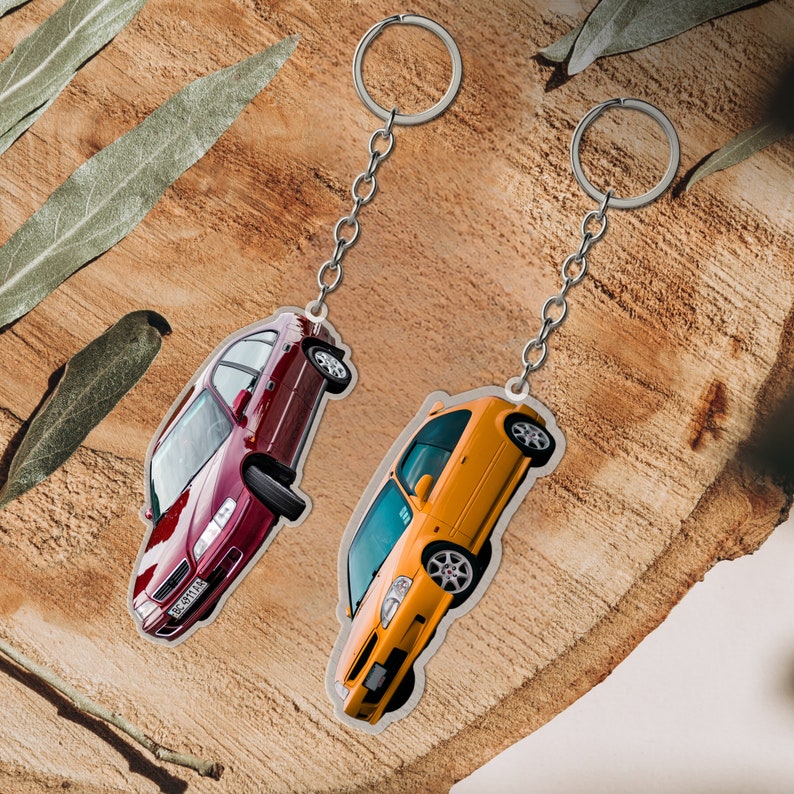May include: Two car keychains, one red and one yellow, with silver key rings. The red car is a Honda Civic and the yellow car is a Honda CRX.