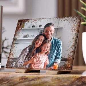 Könnte beinhalten: Ein rustikaler Holz-Bilderrahmen mit einer abgenutzten Oberfläche, der ein Foto einer dreiköpfigen Familie zeigt. Das Foto zeigt einen Mann, eine Frau und ein Kind, die lächeln und in die Kamera schauen.