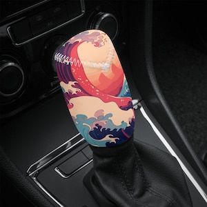 May include: A colourful car gear shift knob with a Japanese wave design. The knob is made of a soft, comfortable material and features a blue, pink and white wave pattern.