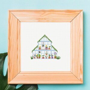 May include: A cross-stitch pattern of a white greenhouse with a light blue roof and green vines. The greenhouse is filled with potted plants in various colors, including pink, purple, yellow, and orange.