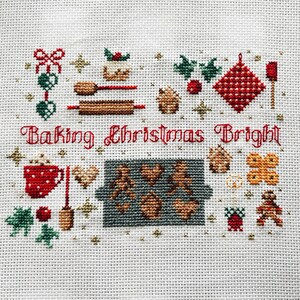 May include: Cross-stitch pattern featuring a festive Christmas baking scene with the text "Baking Christmas Bright". The design includes a gingerbread house, cookies, a rolling pin, a mug of hot chocolate, and other holiday baking elements.