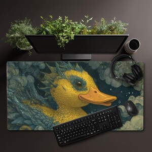 May include: A large rectangular desk mat featuring a yellow duck with blue accents, set against a cloudy background. A black keyboard, mouse, and headphones are visible, along with a computer monitor and a planter with greenery.